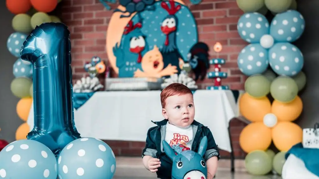 photo of child sitting on toy near balloons