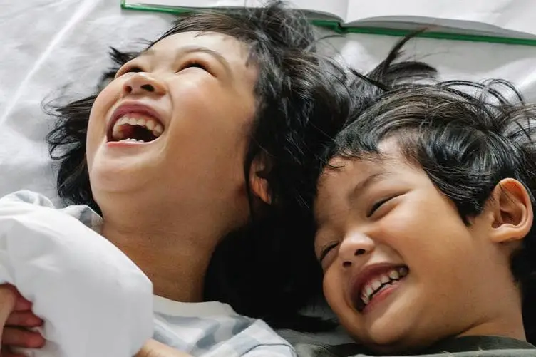 ethnic kids laughing while lying in bed