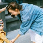 woman in blue denim jacket and white pants holding girl in blue pants