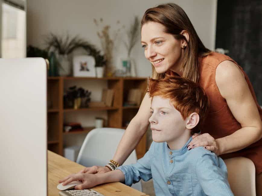 photo of woman and boy looking at imac