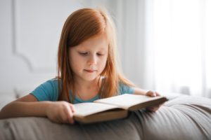 girl in blue t shirt reading book