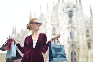 woman wearing maroon velvet plunge neck long sleeved dress while carrying several paper bags photography