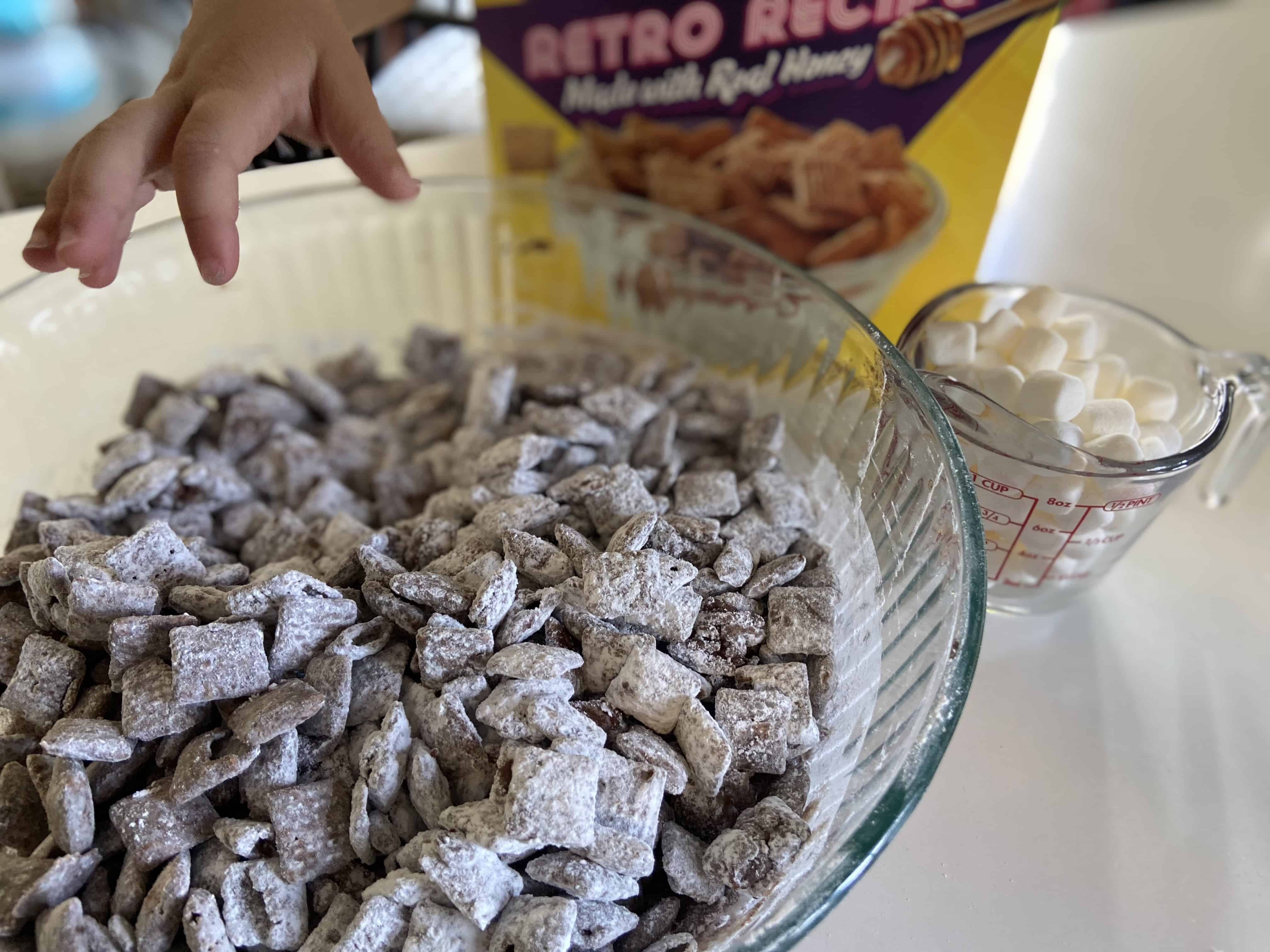 Toddler fingers reaching for puppy chow. 