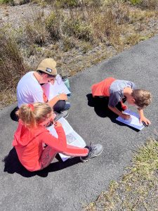 Children completing workbook on path